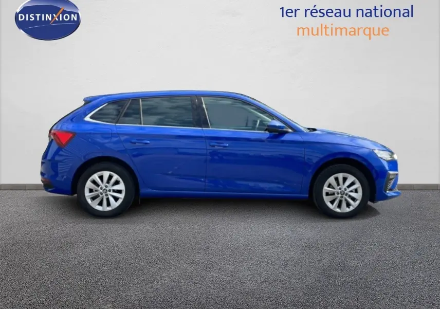 Profil droit d'une Skoda Scala 2025 bleu racing metal avec jantes alliage et vitres teintées, sur fond neutre intérieur.