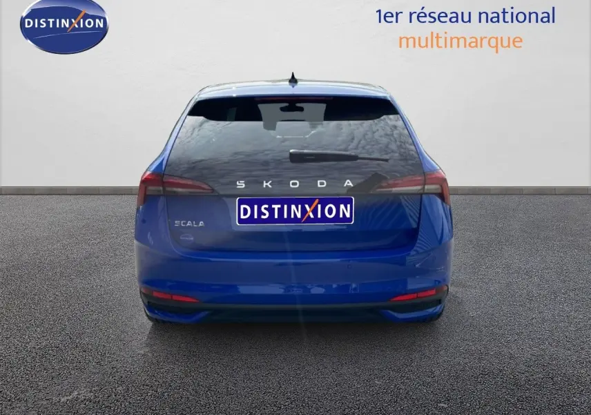 Vue arrière d'une Skoda Scala bleu racing metal 2025, avec feux arrière étirés et logo distinctif au centre.