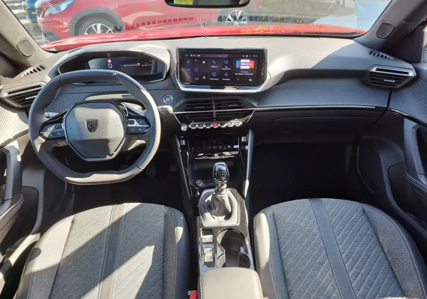 Vue intérieure avant du Peugeot 2008 1.2 PureTech 100 Allure 2023 avec volant compact, écran tactile et levier de vitesse manuel.