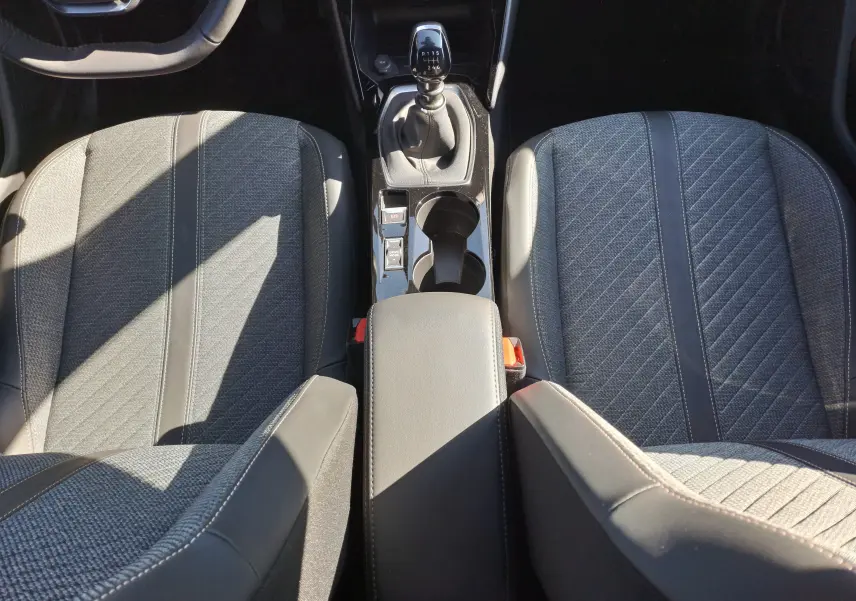 Vue plongeante sur l'intérieur du Peugeot 2008 1.2 PureTech 100 Allure, sièges gris et levier de vitesses manuel.