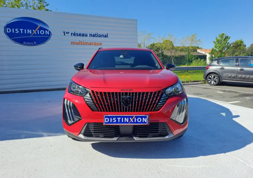 Vue frontale d'un Peugeot 2008 rouge Elixir 2023 avec calandre noire distinctive et phares LED marqués.