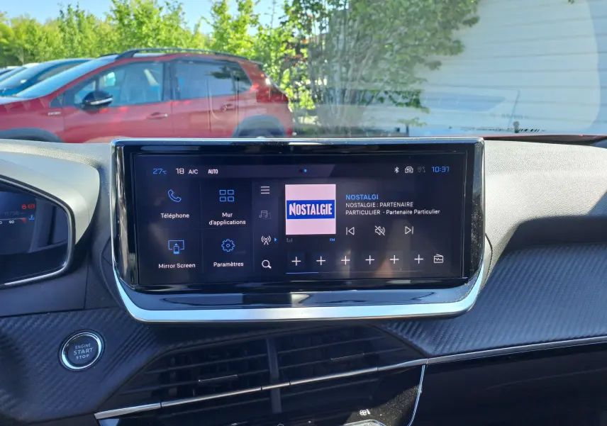 Vue intérieure du tableau de bord du Peugeot 2008 rouge Elixir 2023, avec écran tactile central affichant la radio Nostalgie.