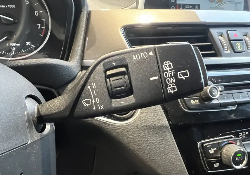 Gros plan sur la commande d'essuie-glace automatique du BMW X1 F48 noir, avec tableau de bord et console centrale visibles.