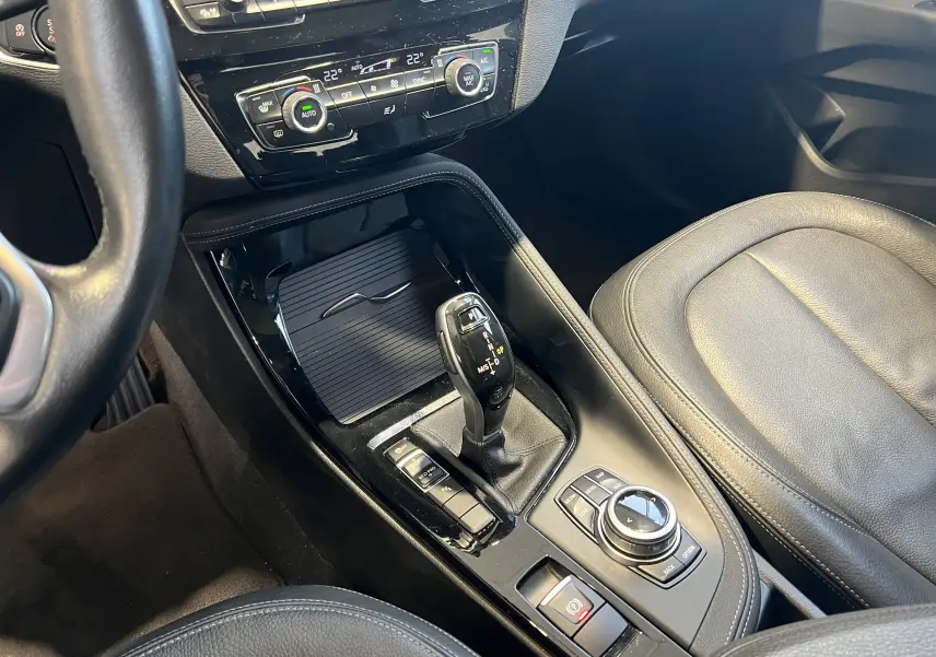 Vue rapprochée de la console centrale noire du BMW X1 F48 2017 avec levier de vitesse automatique et commandes intégrées.