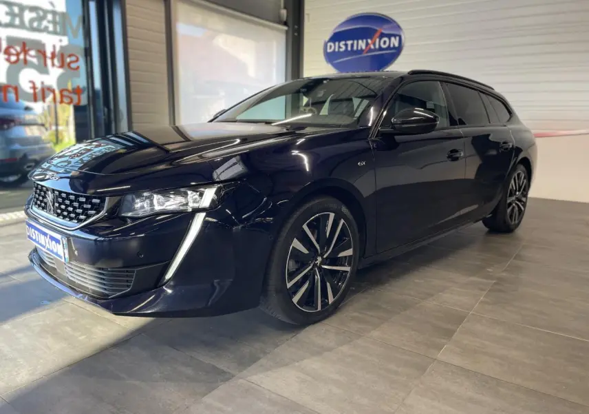 Peugeot 508 SW bleu foncé vue 3/4 avant droit en intérieur avec jantes alliage et calandre distinctive.