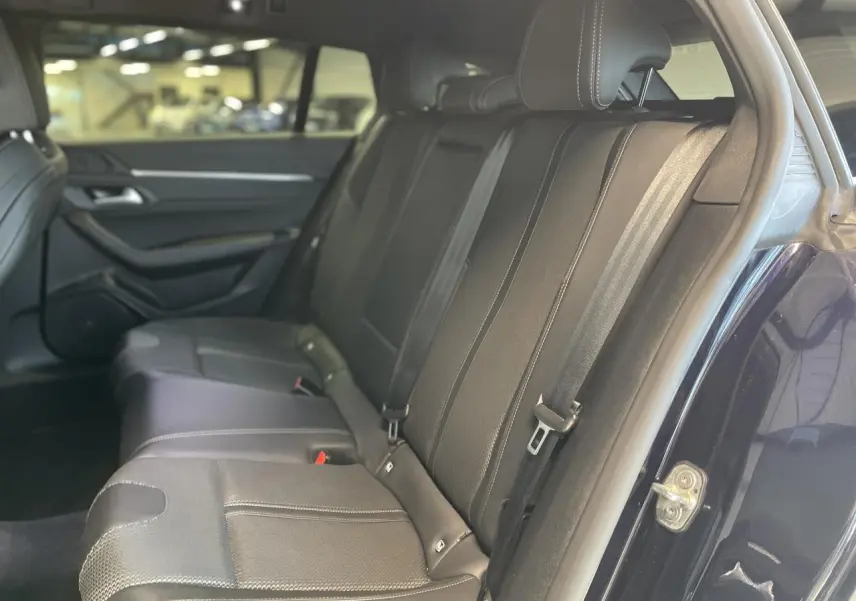 Vue côté droit des sièges arrière en cuir noir de la Peugeot 508 SW bleu foncé, avec ceinture de sécurité visible.