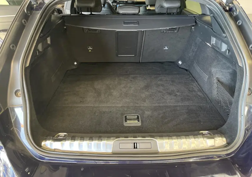 Coffre ouvert d'un break Peugeot 508 SW bleu foncé, montrant un espace de chargement propre et bien fini.