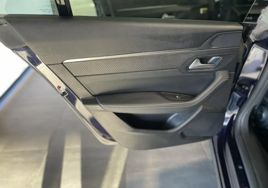 Vue rapprochée de la porte arrière gauche bleu foncé du Peugeot 508 SW avec garniture noire et insert carbone.