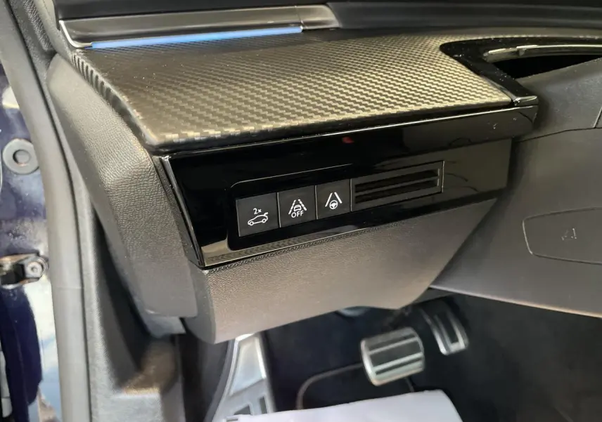 Vue rapprochée des commandes sous le tableau de bord côté gauche d'une Peugeot 508 SW bleu foncé.