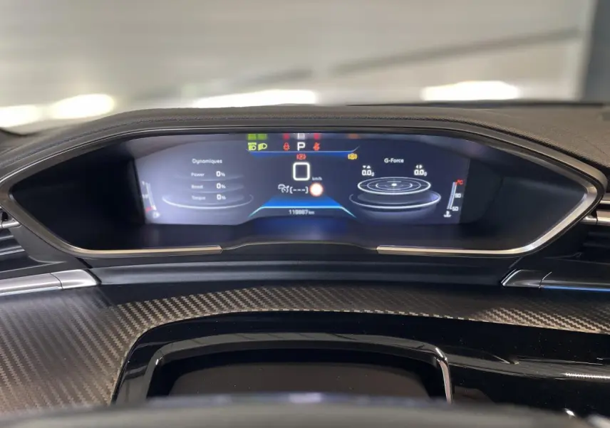 Tableau de bord numérique de Peugeot 508 SW 2021 vu de face, avec affichage des données de conduite et finition carbone.