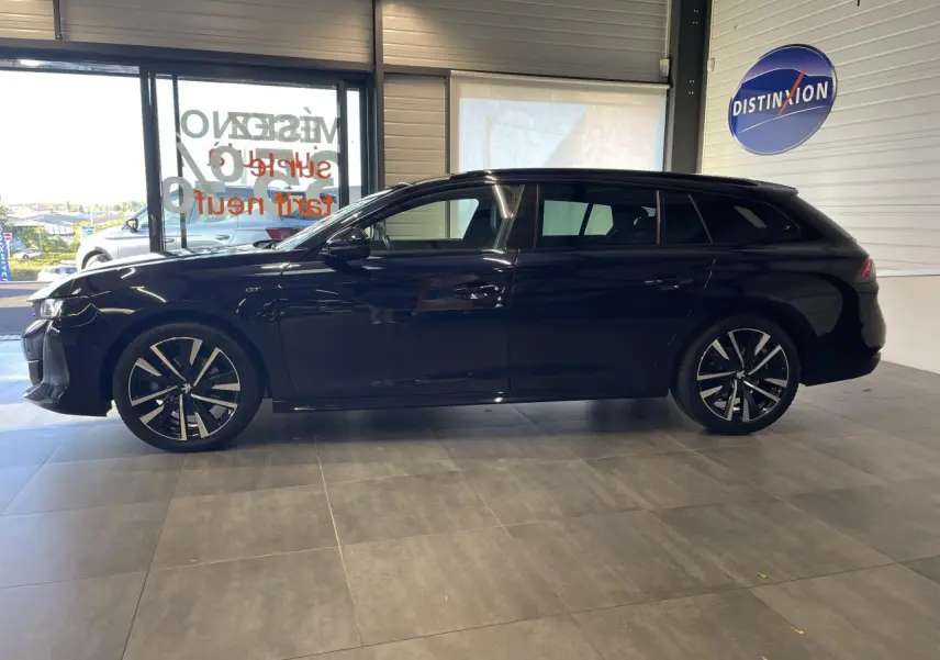 Peugeot 508 SW bleu foncé vue de profil côté gauche en intérieur, avec jantes alliage bi-ton et badge GT visible.