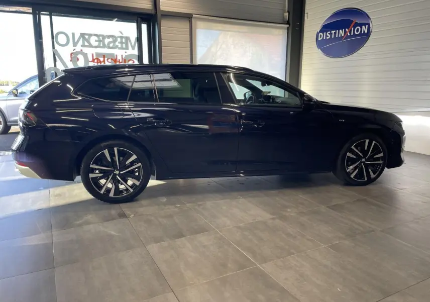Peugeot 508 SW bleu foncé vue de profil côté gauche en intérieur avec jantes alliage noires et diamantées.