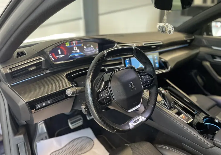 Vue intérieure côté conducteur du Peugeot 508 SW 2021, tableau de bord moderne avec volant compact et écran numérique couleur.