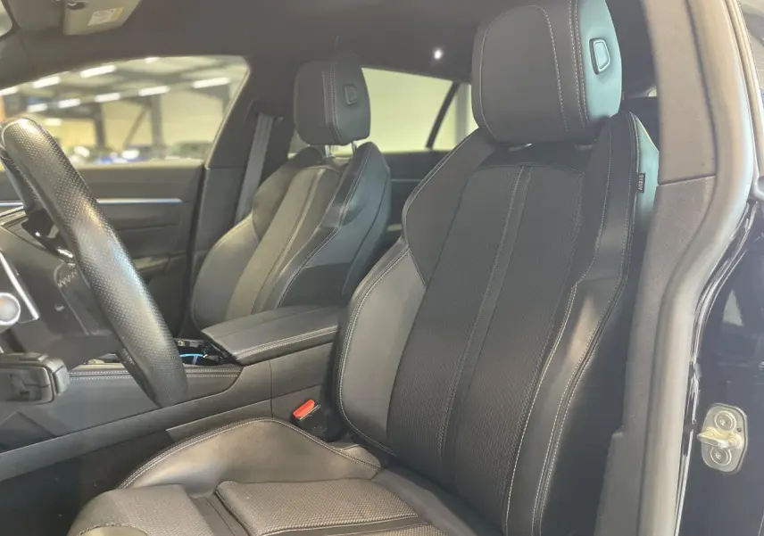 Gros plan sur les sièges avant en cuir noir de la Peugeot 508 SW, avec coutures apparentes et appuie-têtes intégrés.