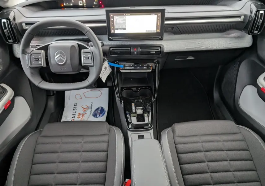 Vue intérieure avant de la Citroën C3 Aircross 2025, planche de bord grise avec écran tactile et volant multifonctions noir.