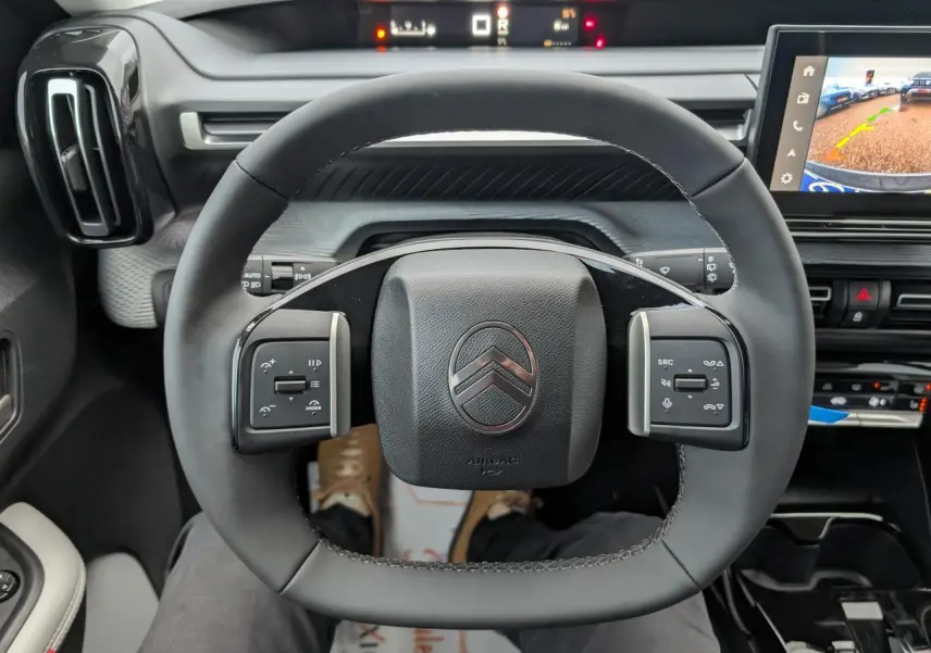 Vue intérieure centrée sur le volant multifonctions noir du Citroën C3 Aircross 2025, avec écran tactile et tableau de bord digital.