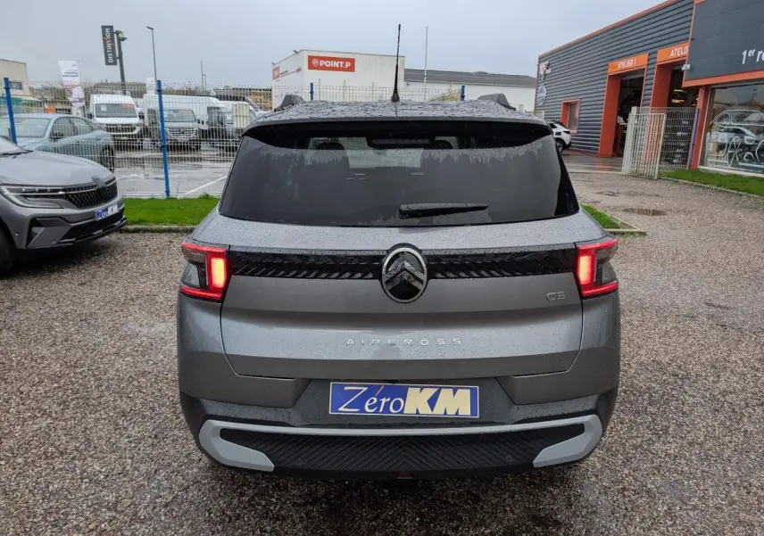 Vue arrière d'un Citroën C3 Aircross gris métallisé avec toit noir et feux arrière LED allumés.