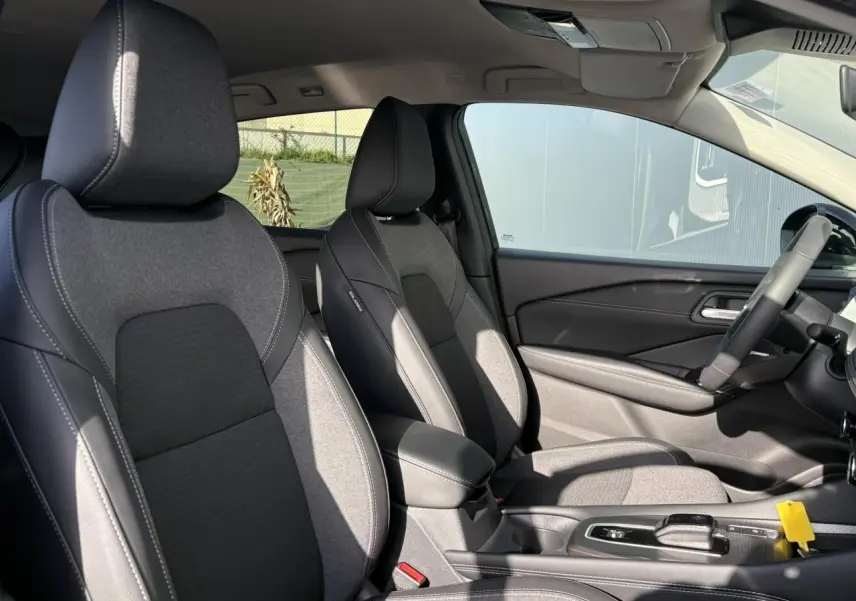 Vue intérieure côté droit montrant les sièges avant gris et noir du Nissan Qashqai III e-Power avec console centrale et volant.