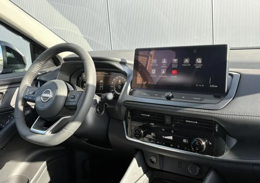 Vue intérieure côté conducteur du tableau de bord noir du Nissan Qashqai 2025 avec écran tactile et volant multifonction.