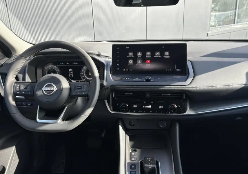 Vue intérieure frontale du tableau de bord noir du Nissan Qashqai III e-Power avec écran tactile et volant multifonction.