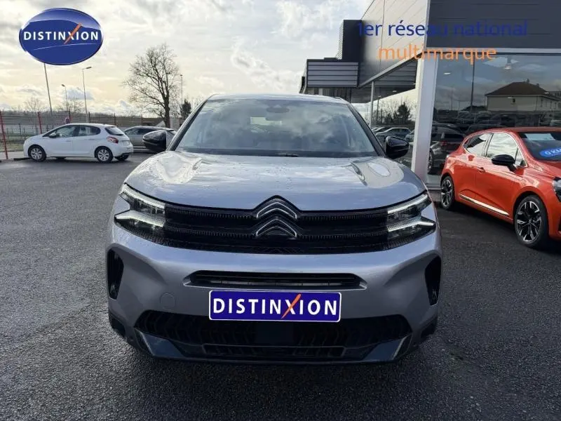 Vue avant d'un Citroën C5 Aircross gris 2024 avec calandre noire et phares LED distinctifs, stationné devant un showroom.