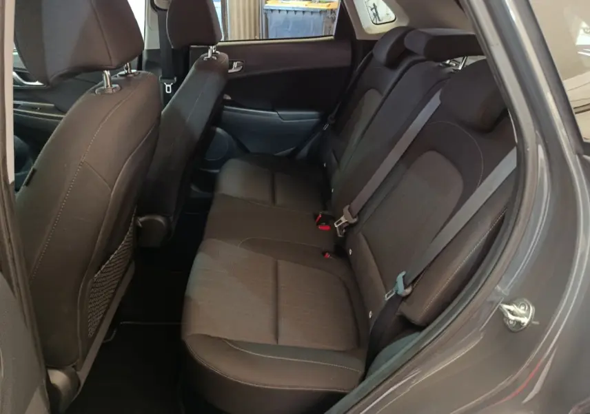 Vue côté droit de la banquette arrière noire du Hyundai Kona 1.6 Hybrid 2023, avec ceintures de sécurité visibles.