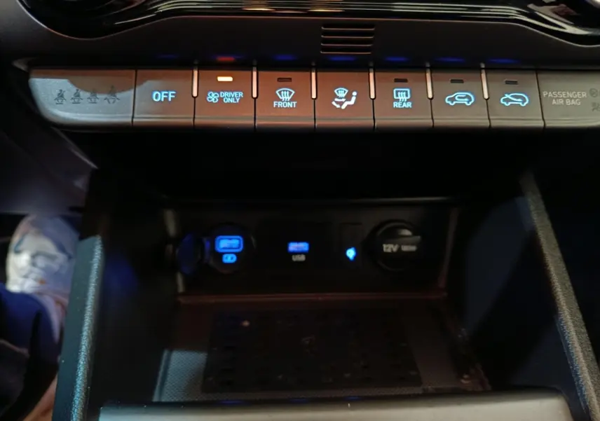 Vue rapprochée du tableau de bord central du Hyundai Kona 2023, montrant les commandes climatisation et prises USB éclairées.