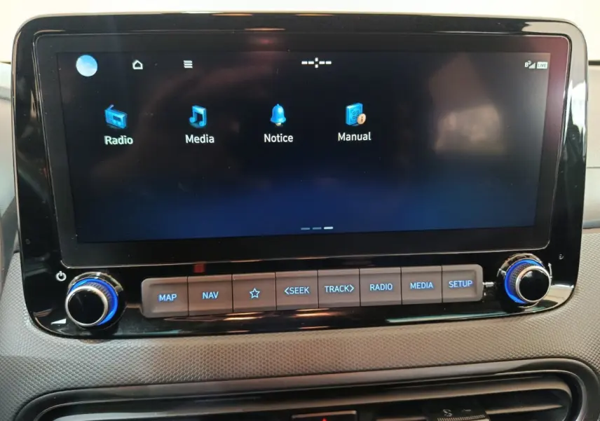 Écran tactile central du tableau de bord de la Hyundai Kona gris foncé, avec commandes multimédia rétroéclairées en bleu.
