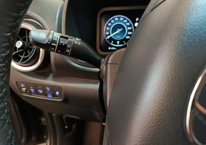 Gros plan sur le volant cuir et la commande des phares à gauche du tableau de bord du Hyundai Kona gris foncé 2023.