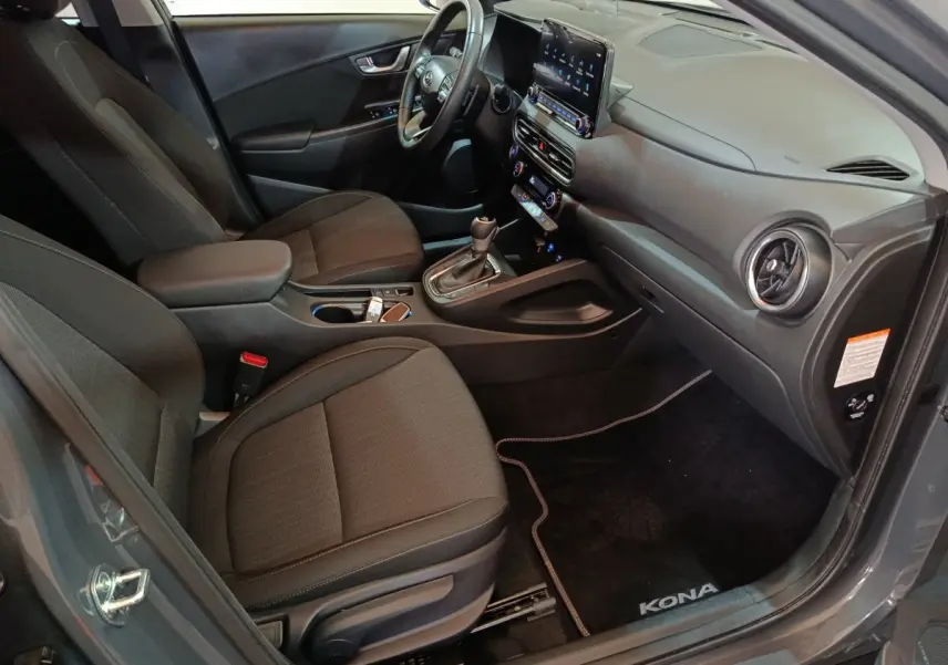 Vue intérieure côté conducteur du Hyundai Kona gris foncé 2023, avec volant cuir multifonctions et écran tactile central.