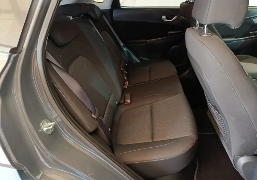 Vue intérieure côté gauche montrant la banquette arrière gris foncé du Hyundai Kona 1.6 Hybrid 2023.
