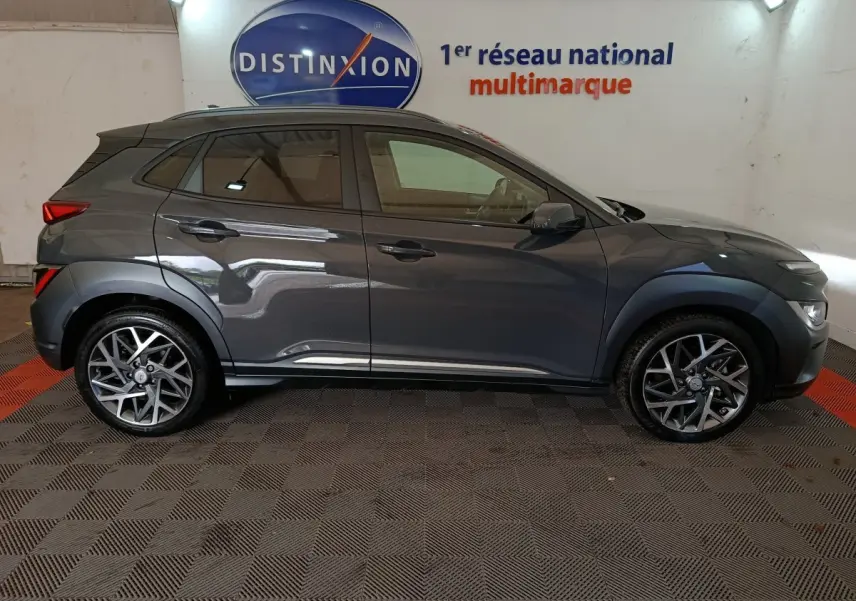 Profil droit d'un Hyundai Kona gris foncé 2023, avec jantes alliage et protections noires sur les passages de roues.