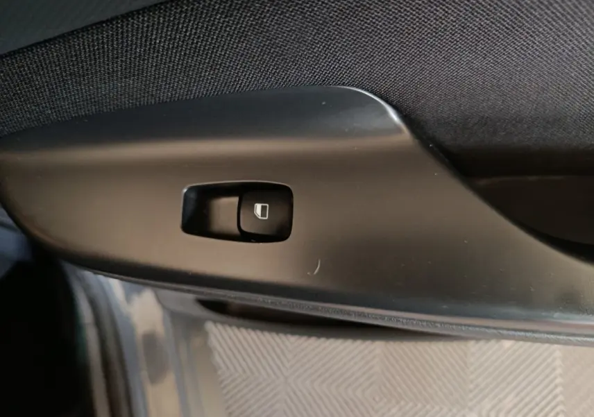 Bouton de commande de vitre électrique sur la porte intérieure côté conducteur d’un Hyundai Kona gris foncé.