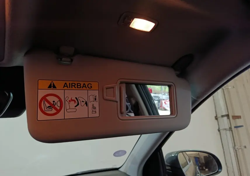 Vue intérieure du pare-soleil côté conducteur avec miroir et avertissement airbag dans un Hyundai Kona gris foncé 2023.