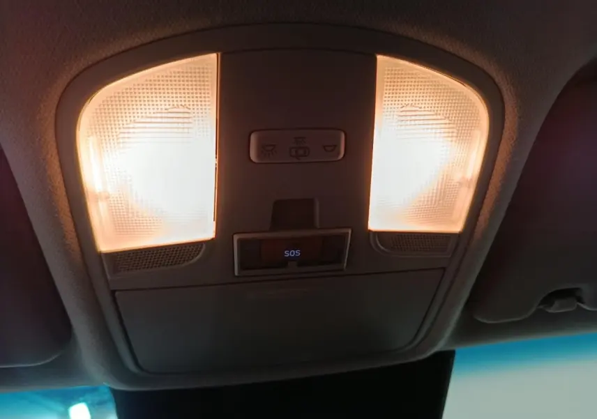 Plafonnier intérieur allumé avec bouton SOS visible dans une Hyundai Kona gris foncé, vue du plafond avant.