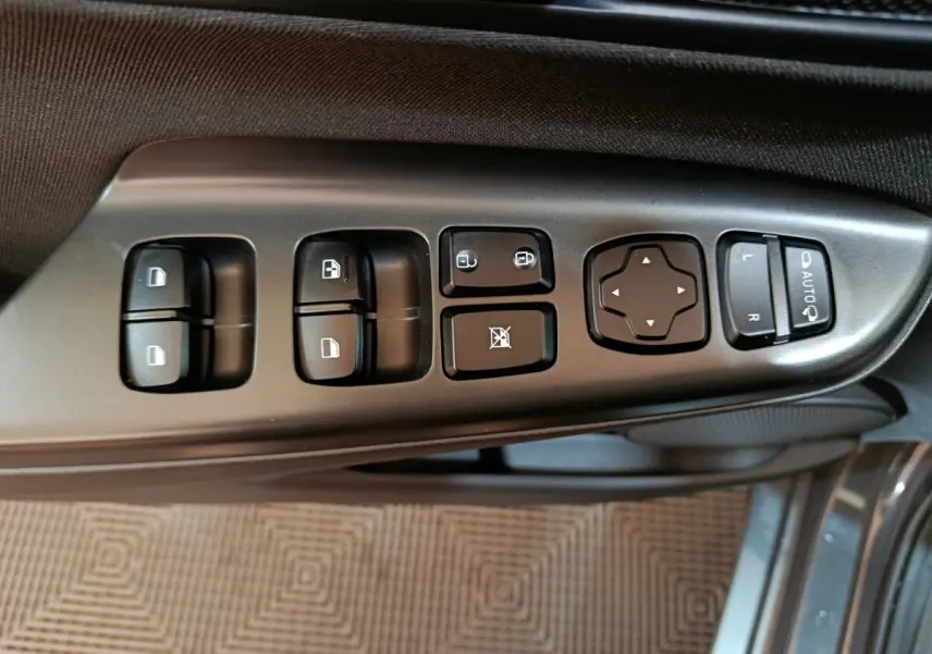 Vue rapprochée des commandes de lève-vitres et rétroviseurs sur la porte côté conducteur d’un Hyundai Kona gris foncé 2023.