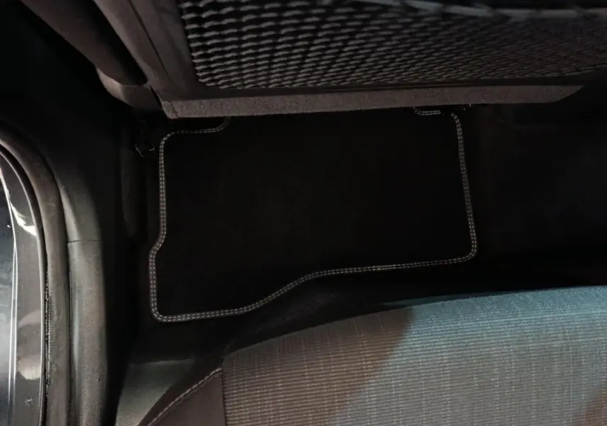 Vue intérieure du plancher arrière côté gauche d'un Hyundai Kona gris foncé avec tapis de sol noir à surpiqûres claires.