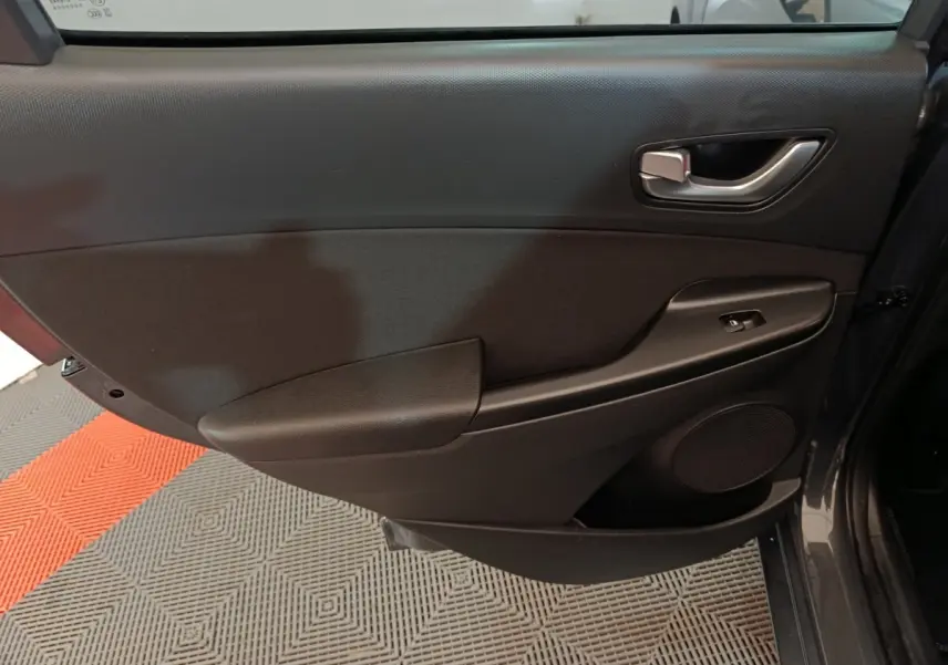 Vue rapprochée de la porte arrière droite gris foncé du Hyundai Kona 1.6 Hybrid 2023 avec poignée et commande de vitre.