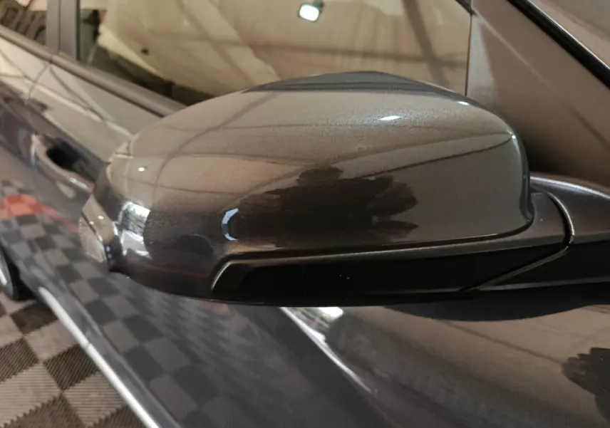 Gros plan sur le rétroviseur droit gris foncé du Hyundai Kona 1.6 Hybrid 2023, avec reflet de l'environnement intérieur.