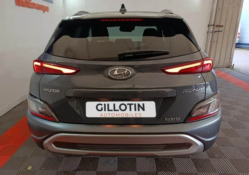 Vue arrière d’un Hyundai Kona gris foncé hybride 2023 avec feux LED allumés et logo Hyundai visible.