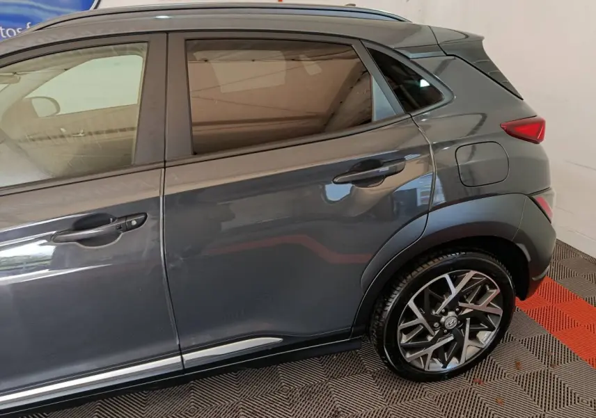 Vue latérale droite sur la partie arrière d’un Hyundai Kona gris foncé avec jante alliage et poignées de porte noires.