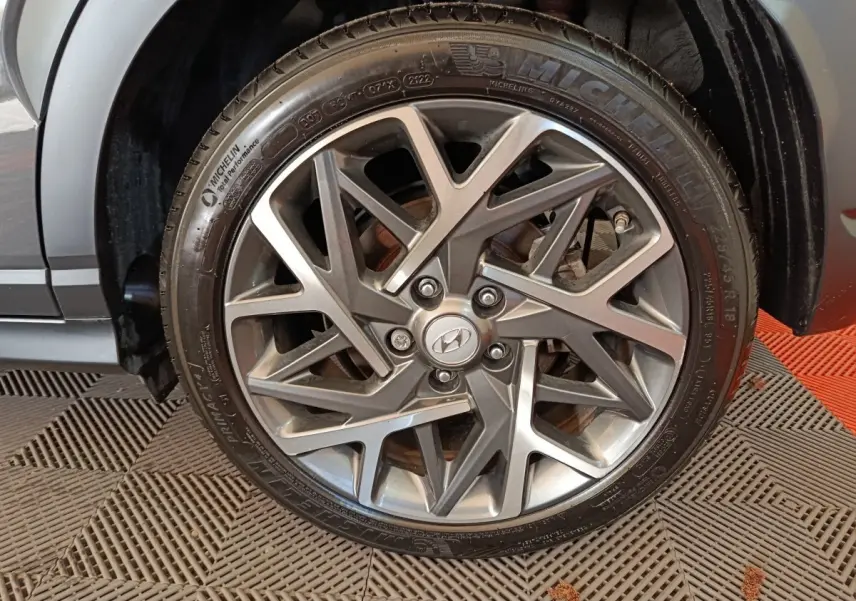 Gros plan sur la roue avant droite de la Hyundai Kona gris foncé, mettant en valeur la jante alliage au design géométrique.