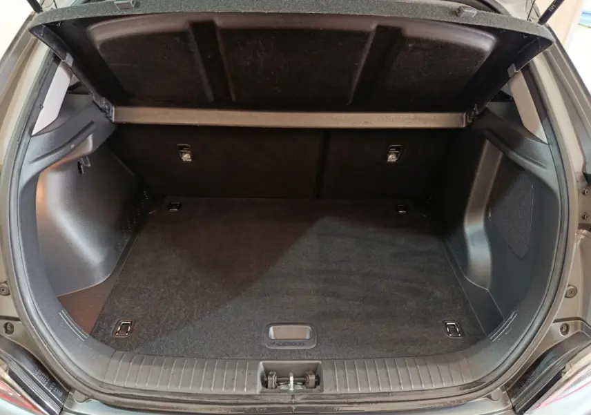 Coffre ouvert vu de l'arrière d'un Hyundai Kona gris foncé, espace de chargement propre et vide.