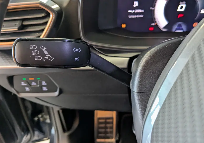 Gros plan sur la manette de clignotants à gauche du volant dans l’habitacle du CUPRA LEON ST gris Magnetic 2025.