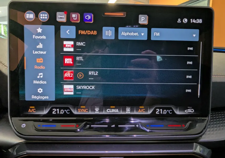Écran tactile central de 12,9 pouces du CUPRA LEON ST 2025 affichant la liste des radios FM avec commandes climatisation intégrées.