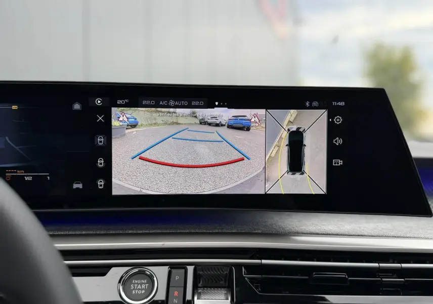 Vue intérieure du tableau de bord du Peugeot 3008 Hybrid 145 GT, écran affichant la caméra de recul et vision 360° en mode stationnement.