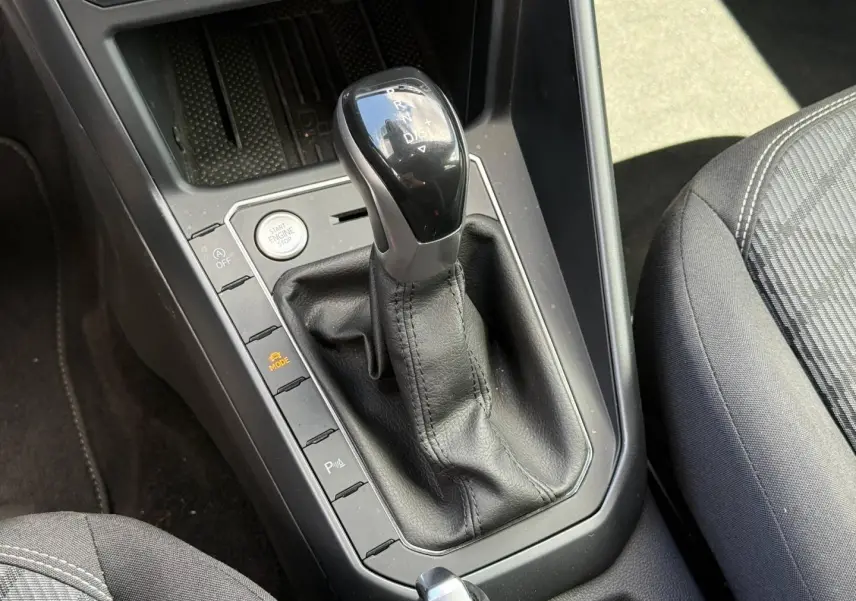 Gros plan sur le levier de vitesses automatique noir et cuir dans l'habitacle gris du Volkswagen Taigo 2025.
