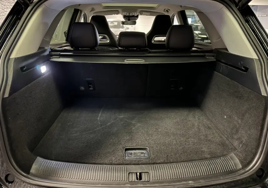 Coffre ouvert vu de l'arrière d'un MG MOTOR EHS noir avec banquette arrière et cache-bagages visibles.