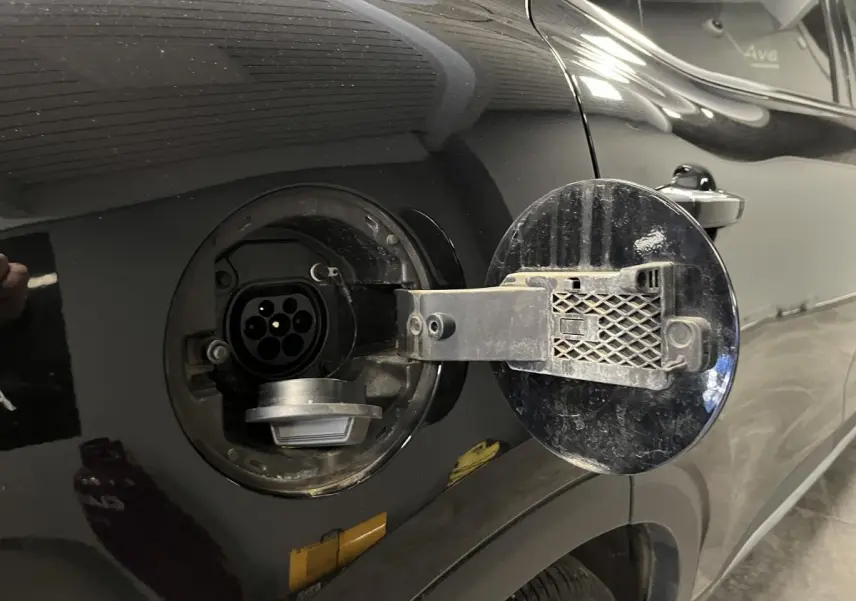 Prise de recharge hybride ouverte côté gauche sur MG MOTOR EHS noire, détail de la trappe et connecteur électrique.