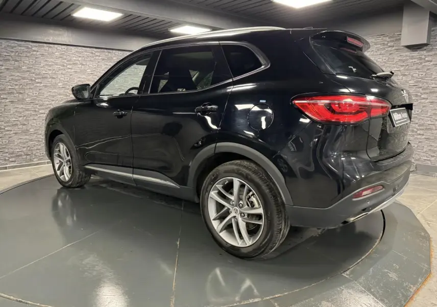 Vue 3/4 arrière droite du MG MOTOR EHS noir métallisé avec jantes alliage et feux arrière LED dans un showroom.